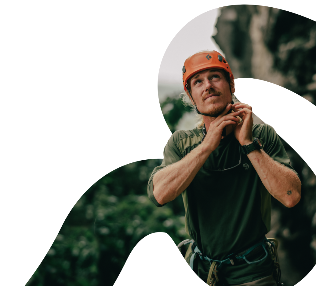 Un grimpeur masculin avec un casque rouge et une chemise verte se reposant et semblant pensif sur fond de falaise rocheuse, encadré dans un dessin circulaire, incarnant l'esprit de « bienvenue » dans son expression de calme